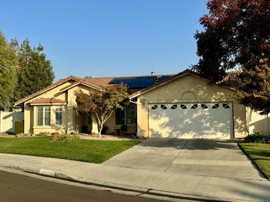 view of front facade with solar panels, a garage, and a front lawn