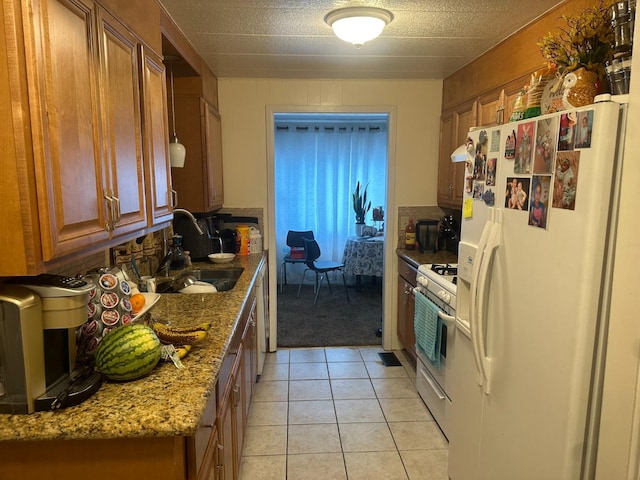 kitchen with light stone counters, white appliances, sink, and light tile patterned floors