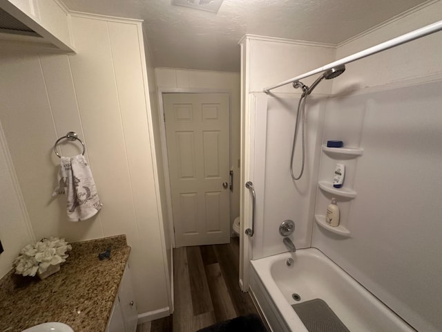 bathroom featuring hardwood / wood-style floors, vanity, shower / washtub combination, ornamental molding, and a textured ceiling