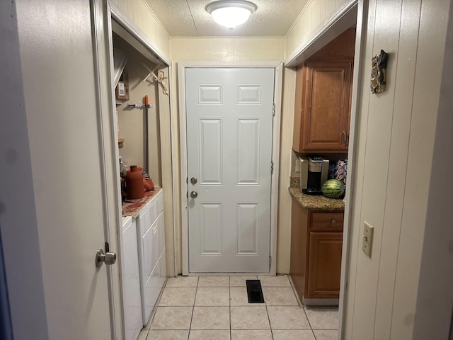 doorway featuring a textured ceiling, washing machine and dryer, and light tile patterned flooring