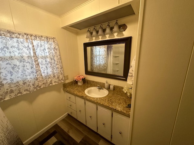 bathroom with crown molding, vanity, and hardwood / wood-style flooring