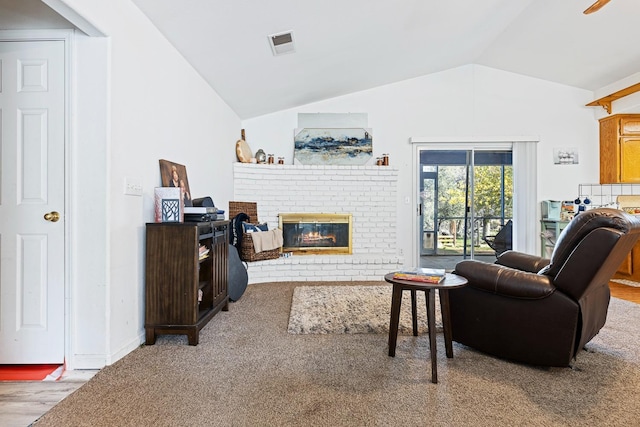 carpeted living room featuring ceiling fan, vaulted ceiling, and a brick fireplace