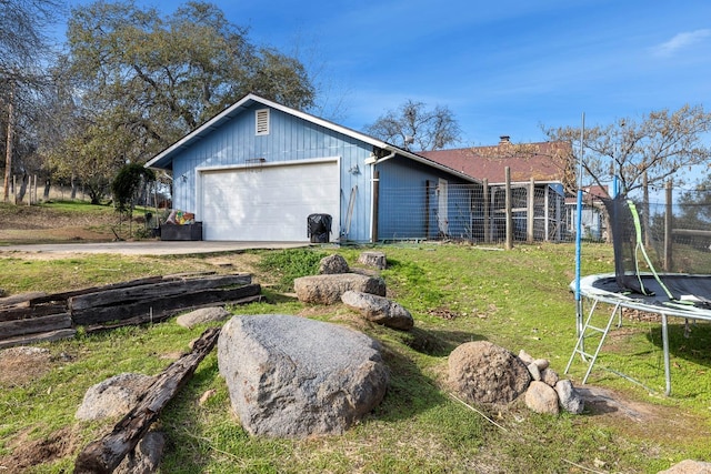 view of side of home featuring a yard, a trampoline, and a garage