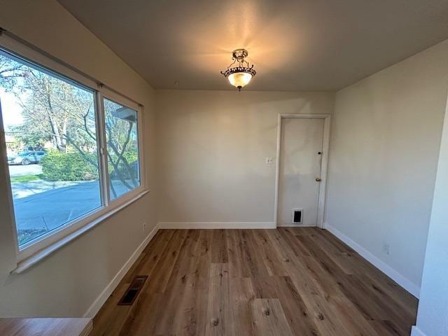 unfurnished dining area featuring visible vents, baseboards, and wood finished floors