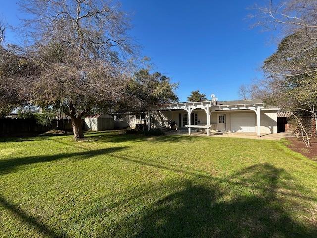 exterior space with a lawn, a patio, an outbuilding, a storage unit, and a pergola