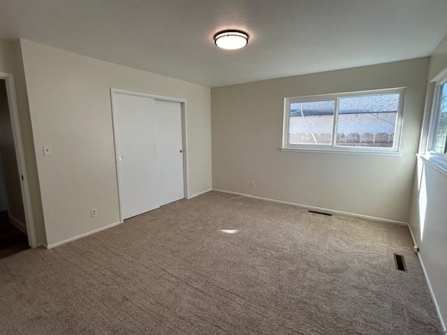 unfurnished bedroom featuring carpet, a closet, visible vents, and baseboards