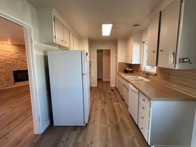 kitchen featuring white appliances, a sink, light wood-style floors, white cabinets, and light countertops