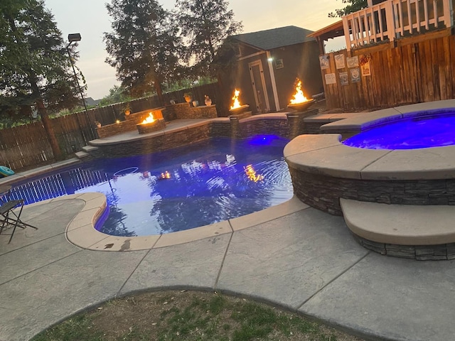 pool at dusk featuring a hot tub and an outdoor fire pit