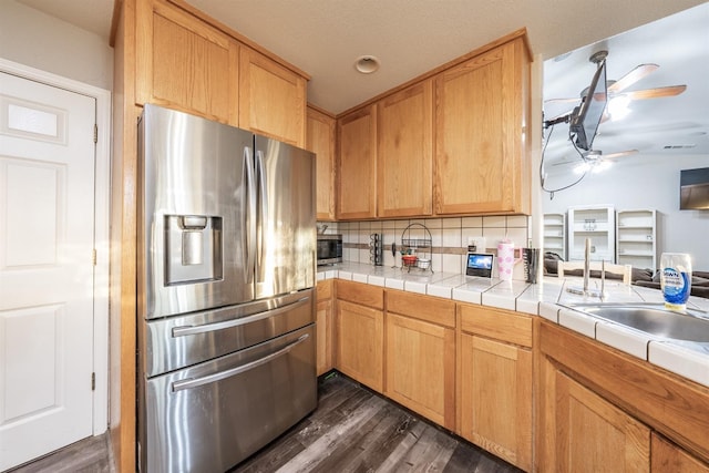 kitchen featuring ceiling fan, tile counters, stainless steel appliances, tasteful backsplash, and dark hardwood / wood-style floors