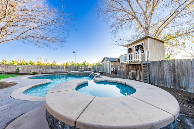 view of pool with an in ground hot tub, pool water feature, and an outdoor structure