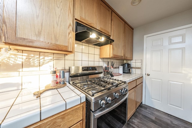 kitchen with dark wood-type flooring, ventilation hood, tasteful backsplash, tile counters, and gas stove