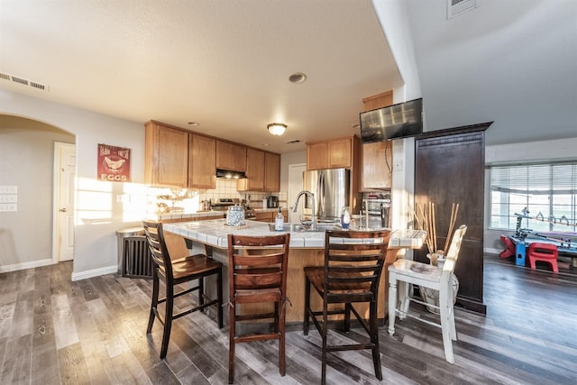 kitchen with kitchen peninsula, dark hardwood / wood-style flooring, stainless steel appliances, and extractor fan