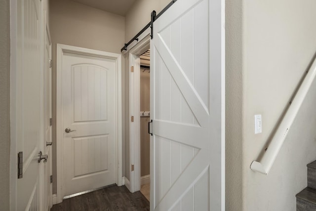 corridor with a barn door and dark wood-type flooring