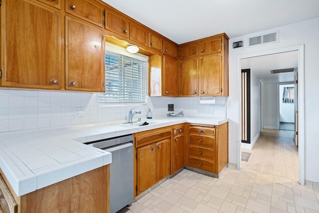 kitchen with backsplash, dishwasher, sink, and tile counters