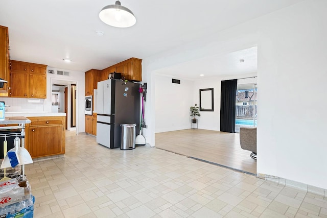 kitchen with backsplash, stainless steel fridge, and oven