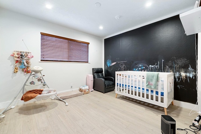 bedroom featuring a crib and wood-type flooring