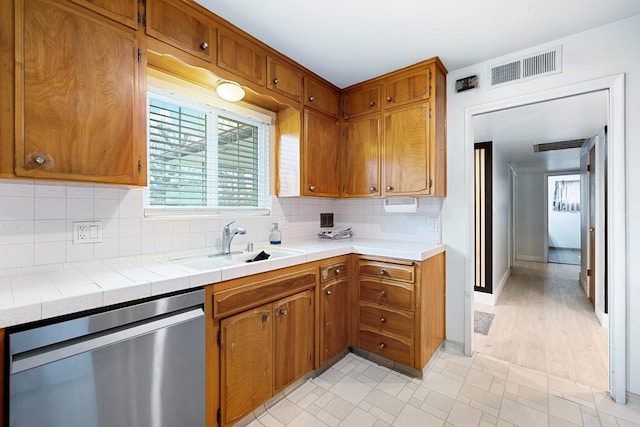 kitchen featuring tile counters, dishwasher, sink, and backsplash