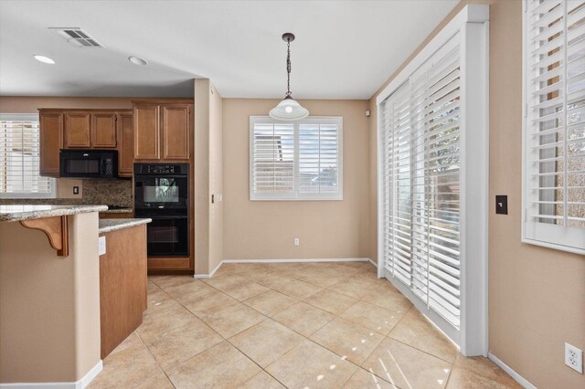 kitchen featuring pendant lighting, backsplash, black appliances, light tile patterned floors, and a healthy amount of sunlight