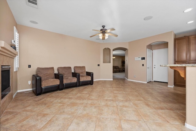 living room featuring a tile fireplace, ceiling fan, and light tile patterned floors