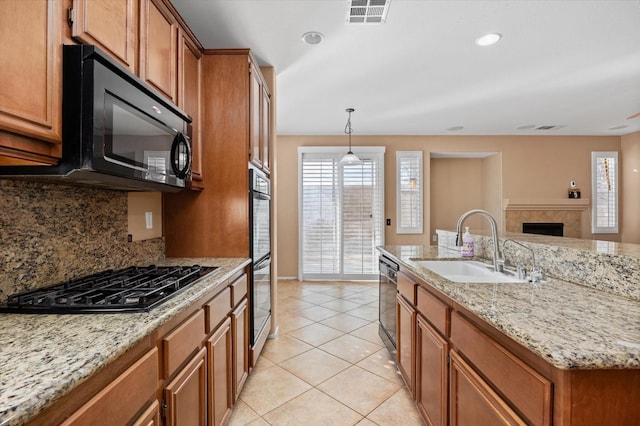 kitchen with backsplash, sink, black appliances, hanging light fixtures, and light tile patterned flooring