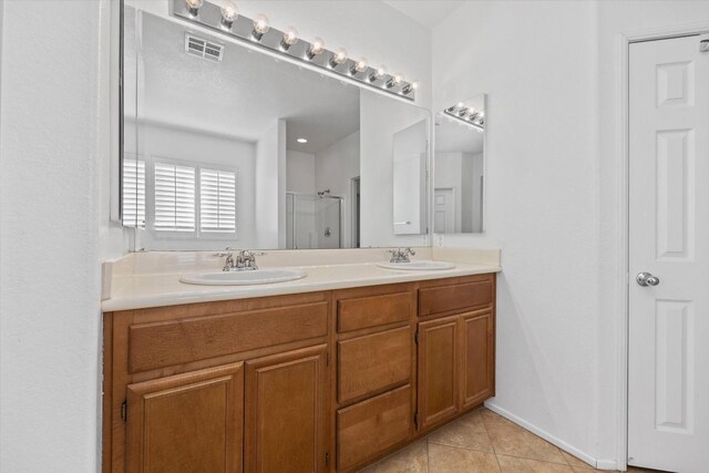 bathroom featuring tile patterned floors, a shower with door, and vanity