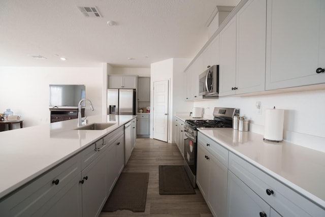 kitchen featuring dark wood-type flooring, sink, a textured ceiling, white cabinetry, and stainless steel appliances