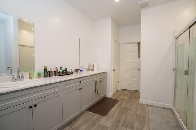 bathroom with hardwood / wood-style flooring, vanity, and an enclosed shower