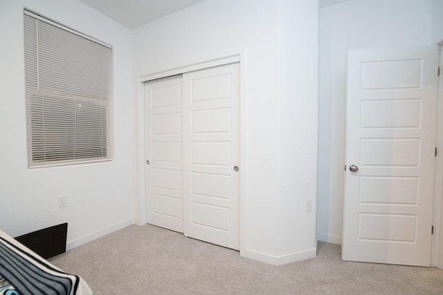 unfurnished bedroom featuring light carpet and a closet