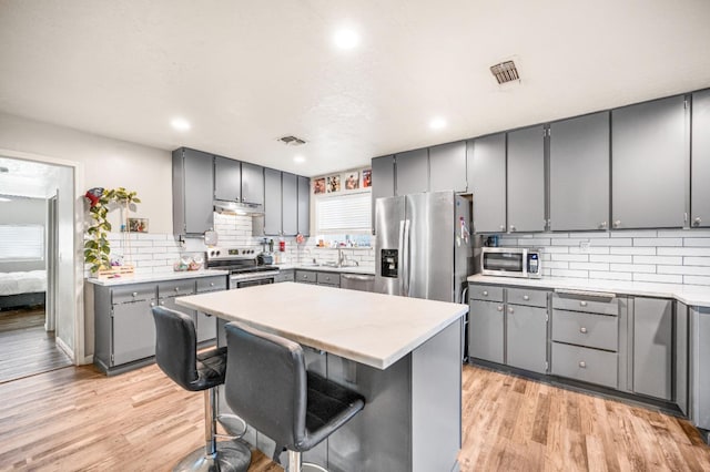 kitchen featuring a kitchen breakfast bar, gray cabinets, and appliances with stainless steel finishes