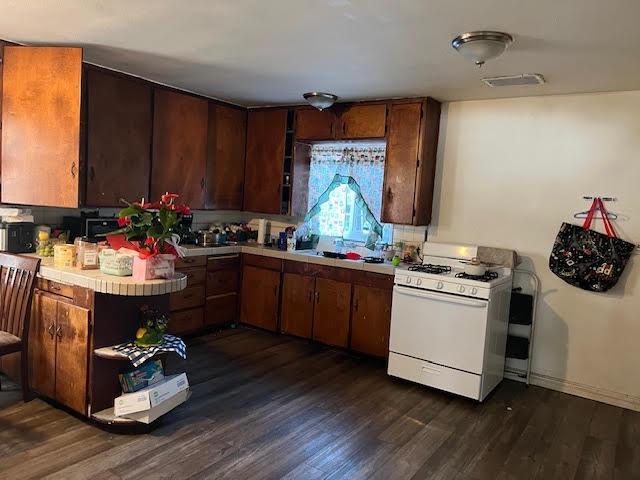 kitchen featuring dark brown cabinetry, dark wood-type flooring, and white gas range oven