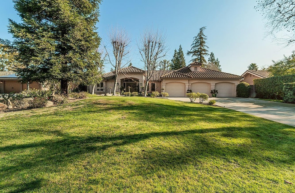 mediterranean / spanish house featuring a garage and a front lawn