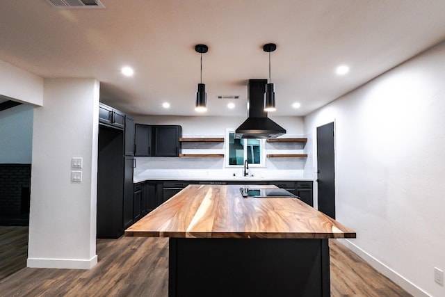 kitchen with sink, decorative light fixtures, a center island, island exhaust hood, and wooden counters