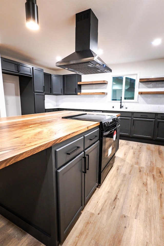 kitchen featuring wooden counters, black range with electric stovetop, light hardwood / wood-style floors, sink, and exhaust hood