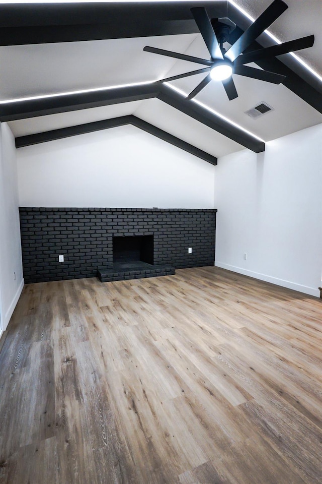 unfurnished living room with ceiling fan, hardwood / wood-style floors, lofted ceiling with beams, and a fireplace