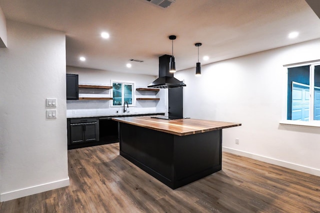 kitchen featuring island exhaust hood, a center island, butcher block countertops, decorative light fixtures, and backsplash