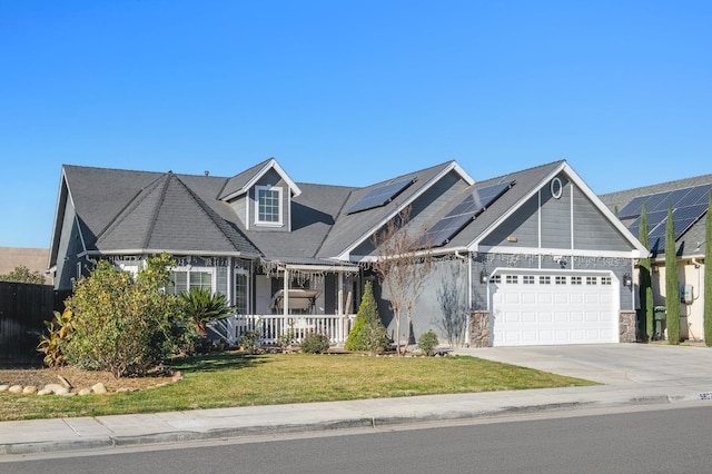 view of front of home featuring a front lawn, covered porch, a garage, and solar panels