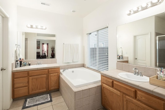 bathroom featuring tiled tub, tile patterned flooring, and vanity