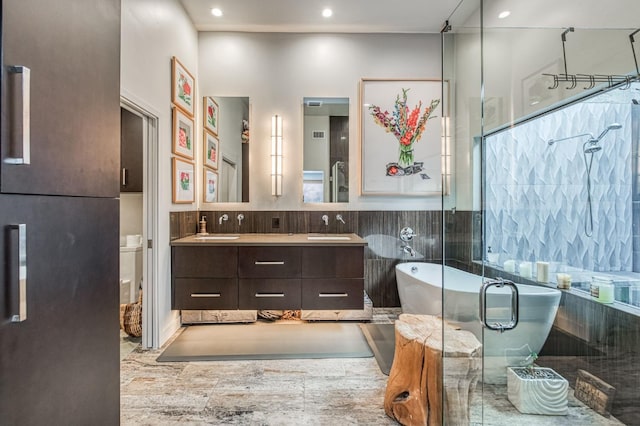 bathroom with a soaking tub, a shower stall, recessed lighting, a sink, and double vanity