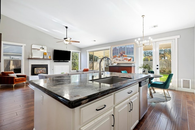 kitchen featuring lofted ceiling, sink, a center island with sink, dark stone counters, and white cabinets