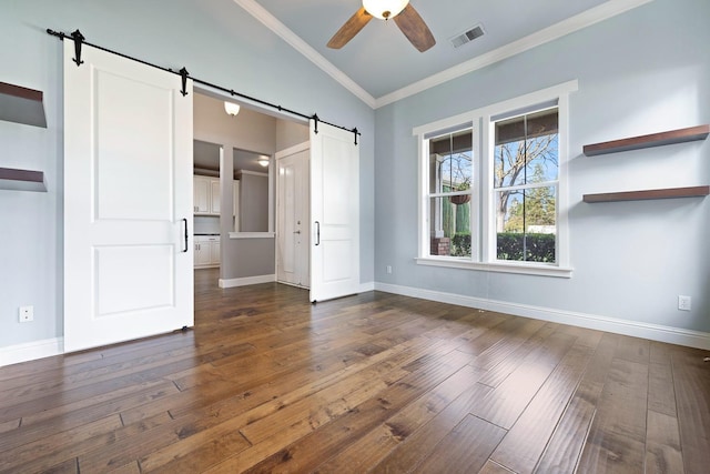 unfurnished bedroom with lofted ceiling, dark wood-type flooring, ornamental molding, and a barn door