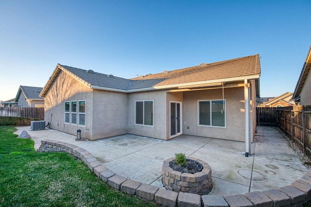 rear view of house with cooling unit, a fire pit, and a patio area