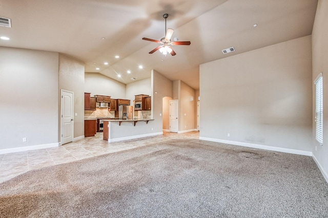 unfurnished living room with high vaulted ceiling, light colored carpet, and ceiling fan