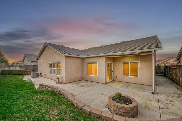 back house at dusk with a patio, a yard, central AC, and an outdoor fire pit