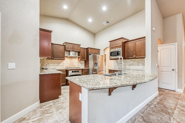 kitchen with sink, a kitchen breakfast bar, kitchen peninsula, stainless steel appliances, and light stone countertops