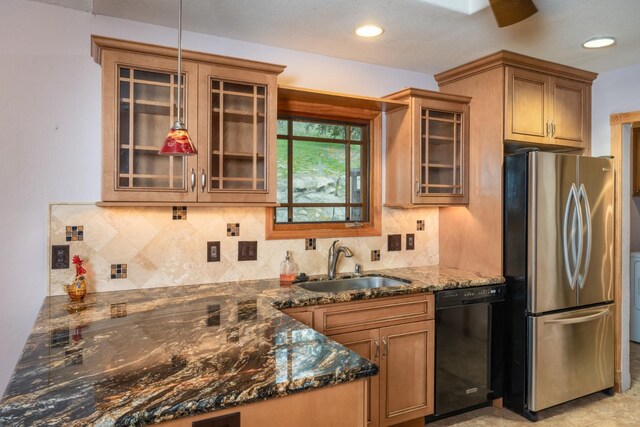 kitchen featuring sink, stainless steel refrigerator, dark stone countertops, backsplash, and black dishwasher