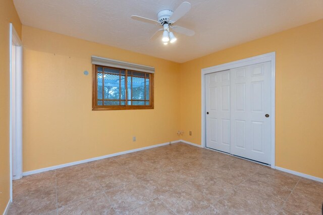 unfurnished bedroom with ceiling fan and a closet