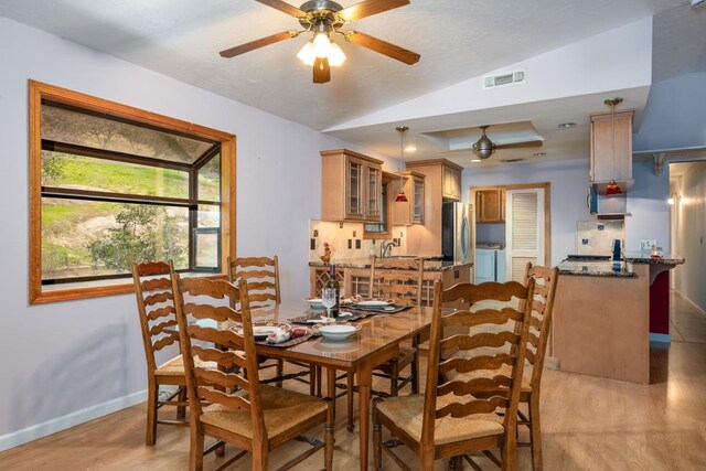 dining room featuring ceiling fan, lofted ceiling, light wood-type flooring, and independent washer and dryer