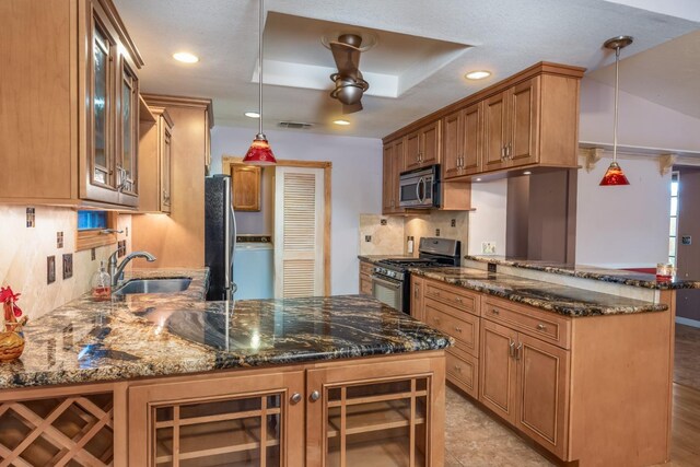 kitchen with stainless steel appliances, dark stone countertops, pendant lighting, and kitchen peninsula