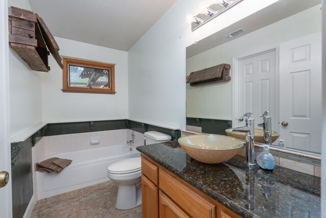 bathroom featuring vanity, a tub to relax in, and toilet