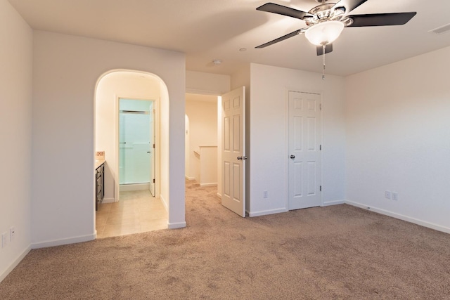 unfurnished bedroom with ensuite bath, ceiling fan, and light colored carpet